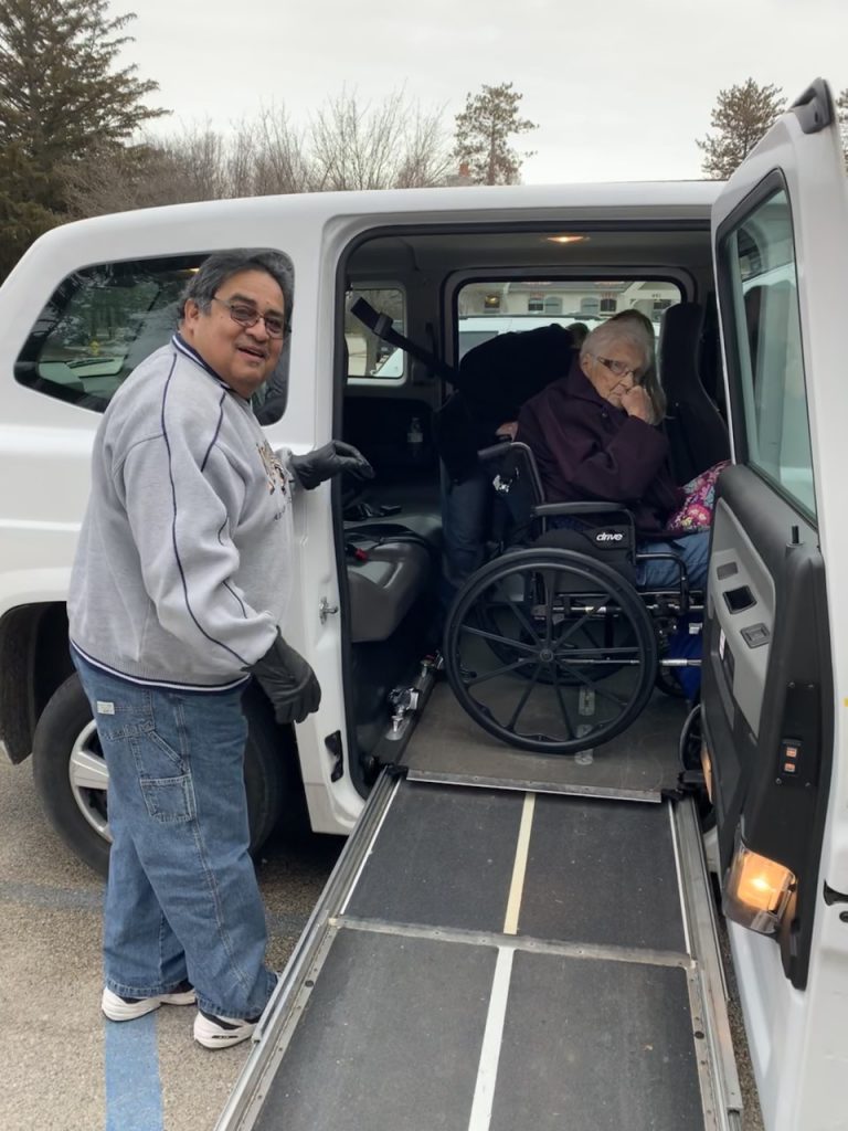 A volunteer helps a participant in and out of a Senior Transportation vehicle.